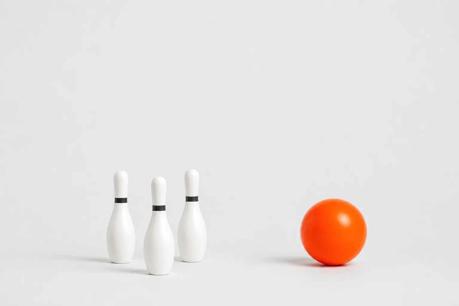 An orange duckpin ball and three duckpin pins